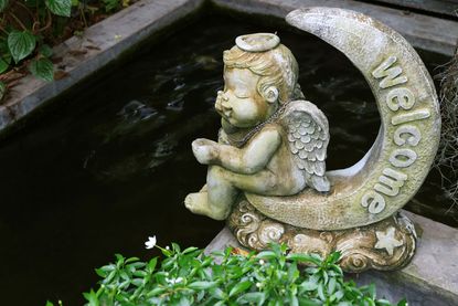 Garden Statue Of A Baby Sitting On The Moon