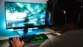 A PC gamer using an RGB gaming keyboard and a Logitech gaming headset.