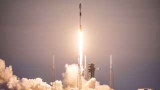 a white and black rocket launches into a dusk sky, leaving behind a puffy plume