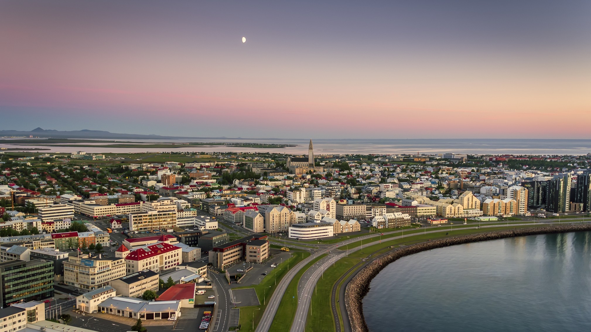 a city skyline, above the sky is colored hues of pink yellow and blue.
