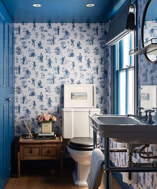 Blue toile style wallpaper, blue walls and ceiling, trad basin, vintage side table, stripe blind