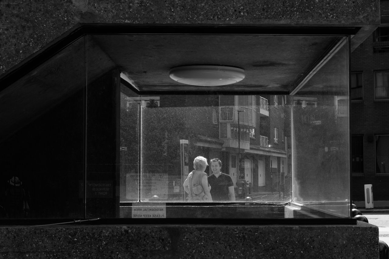 Two people talking through a glass window