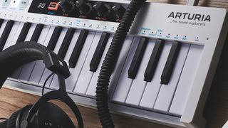 Arturia KeyStep 37 controller next to a pair of studio headphones