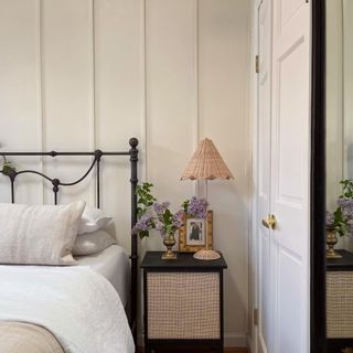 A bedroom with a panelled wall painted in Lick's White 03 paint and a bed in front of it with a contrasting black metal headboard