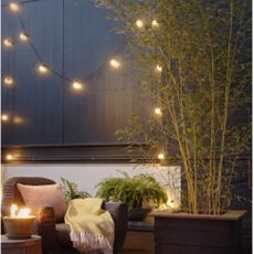 garden terrace area, with patterned paving, firepit and outdoor lighting, bamboo and foliage plants, garden chair and table