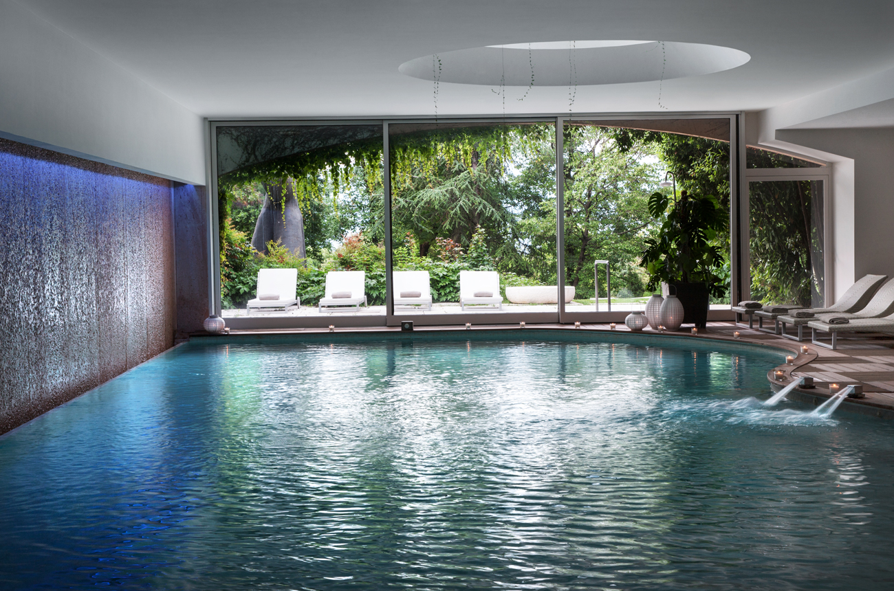 An indoor swimming pool overlooking lush gardens in Italy
