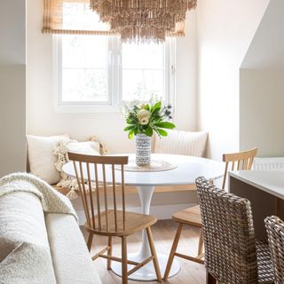 Fresh dining nook with round white pedestal table, spindle dining chairs ans statement natural chandelier