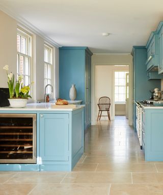 can you fit an island in a galley kitchen, pale blue and cream kitchen with stone tile floor, small kitchen island, wine cooler, white countertops