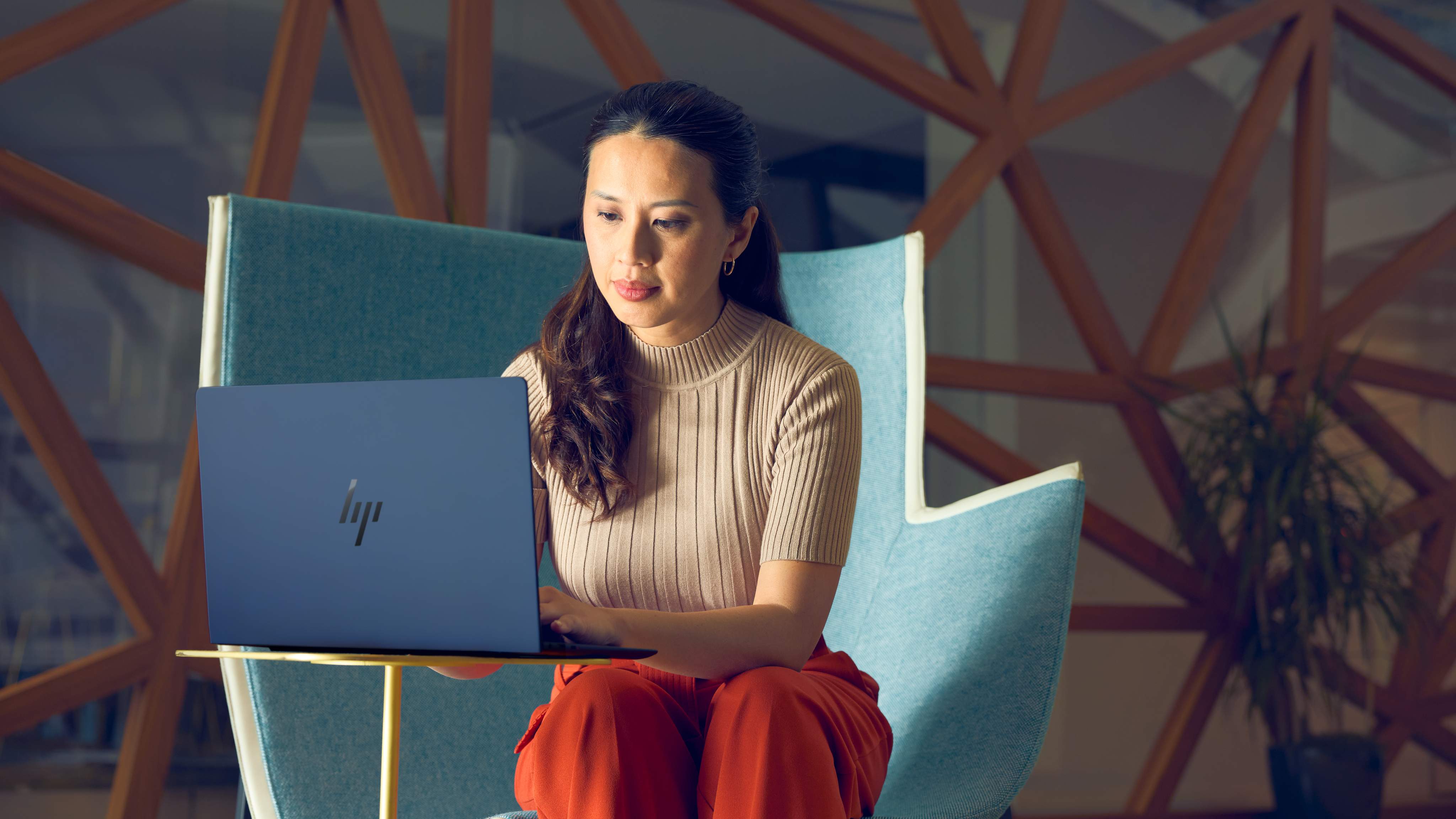 A person sitting at a small table while using the HP EliteBook Ultra 14 (G1i).