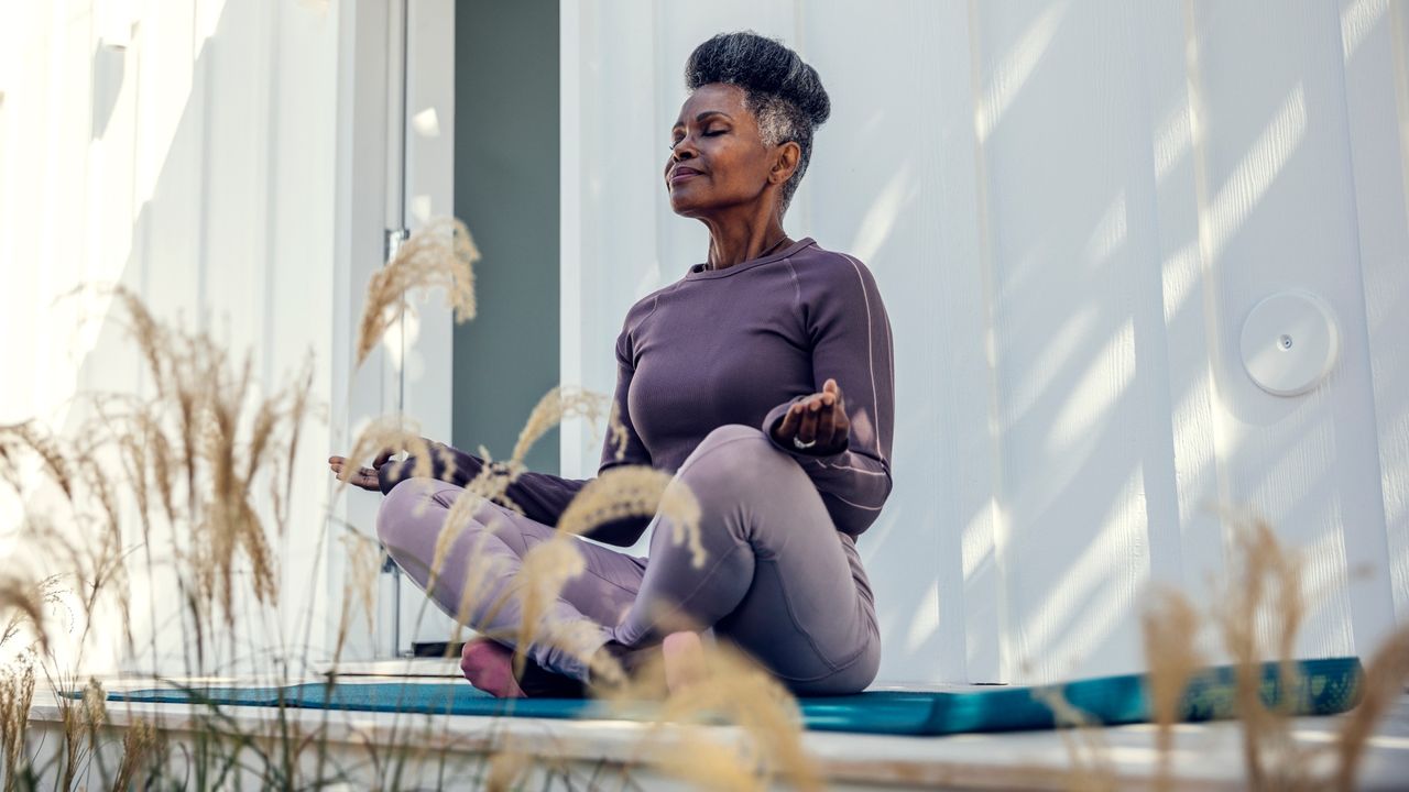 Shadow work: Mature woman meditating in backyard - stock photo