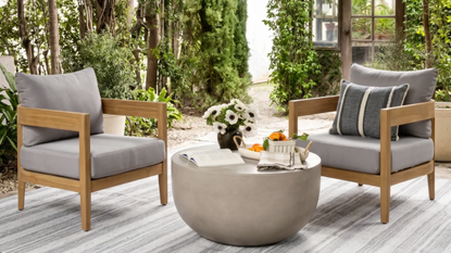 a patio scene with two chairs, a coffee table, and a striped gray rug