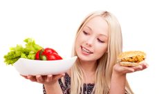 A woman chooses between a healthy salad and a fried chicken sandwich. 