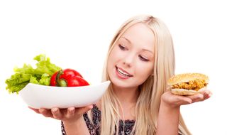 A woman chooses between a healthy salad and a fried chicken sandwich. 