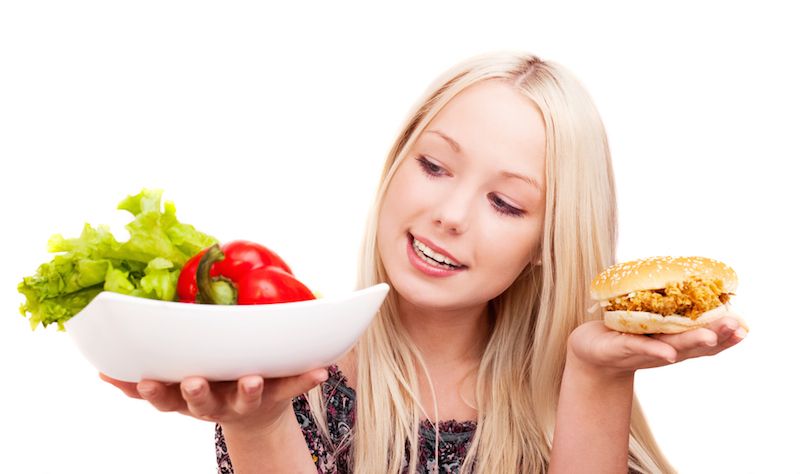 A woman chooses between a healthy salad and a fried chicken sandwich. 