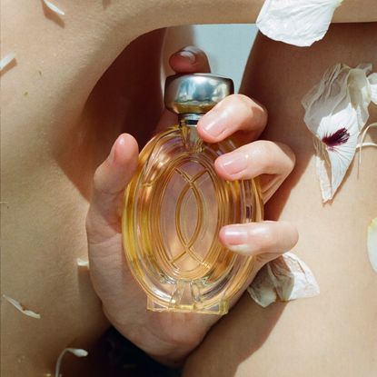 a close up of a hand holding a glass bottle of perfume