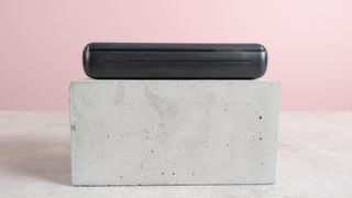 Side view of Jiga 27000mAh Power Bank on plinth with pink background