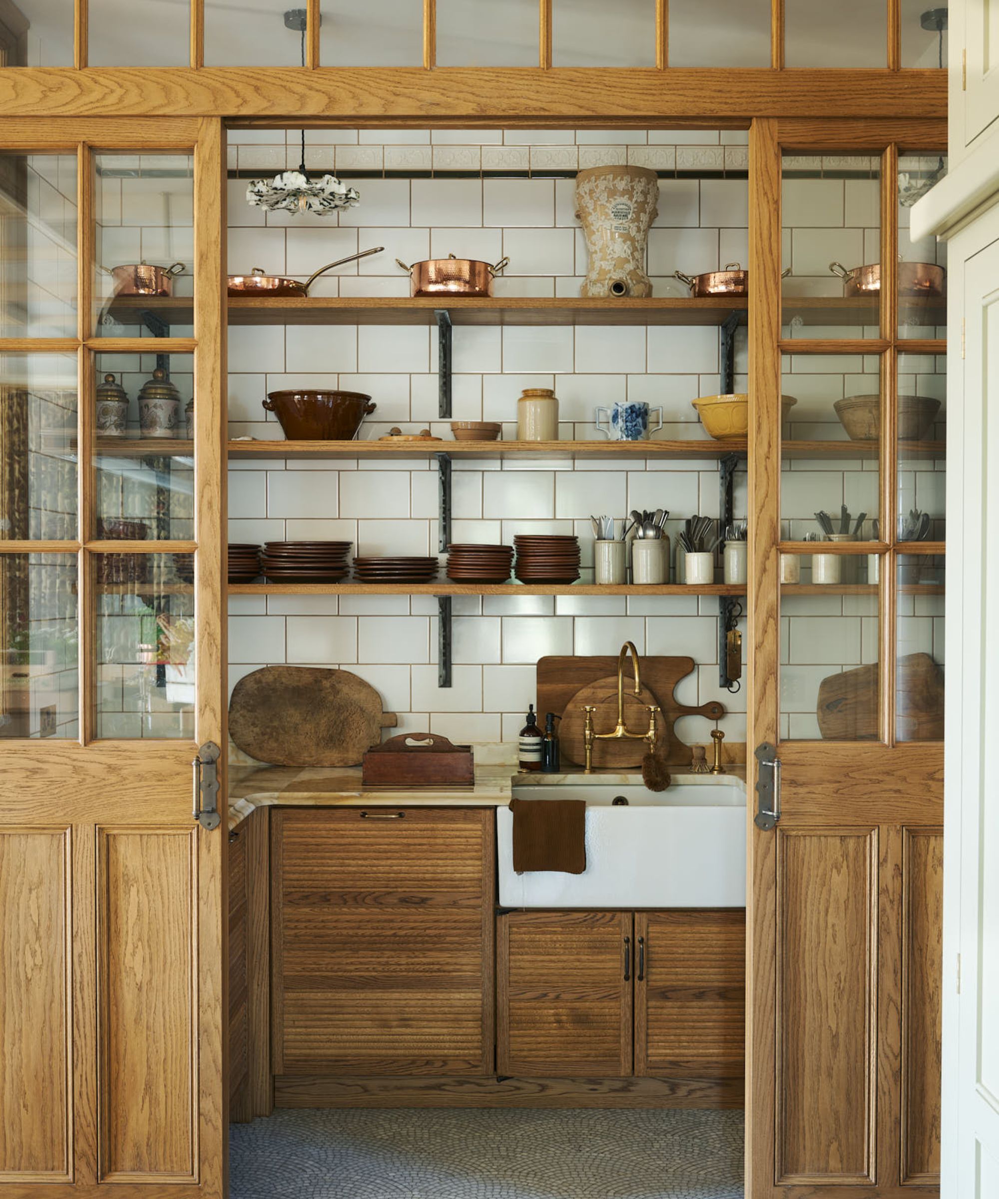 A glass-framed pantry filled with open shelves to store plates and dried goods