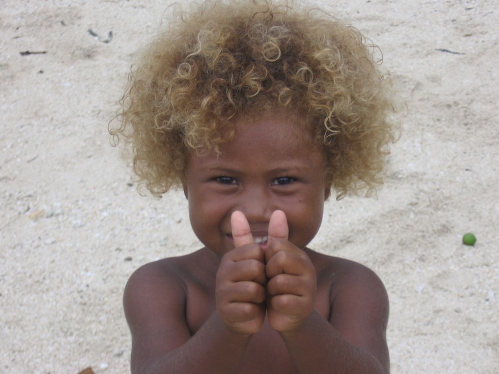 A blond-haired Solomon Island child smiles for the camera