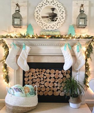 A fireplace with stockings, pine garlands, and a mirror
