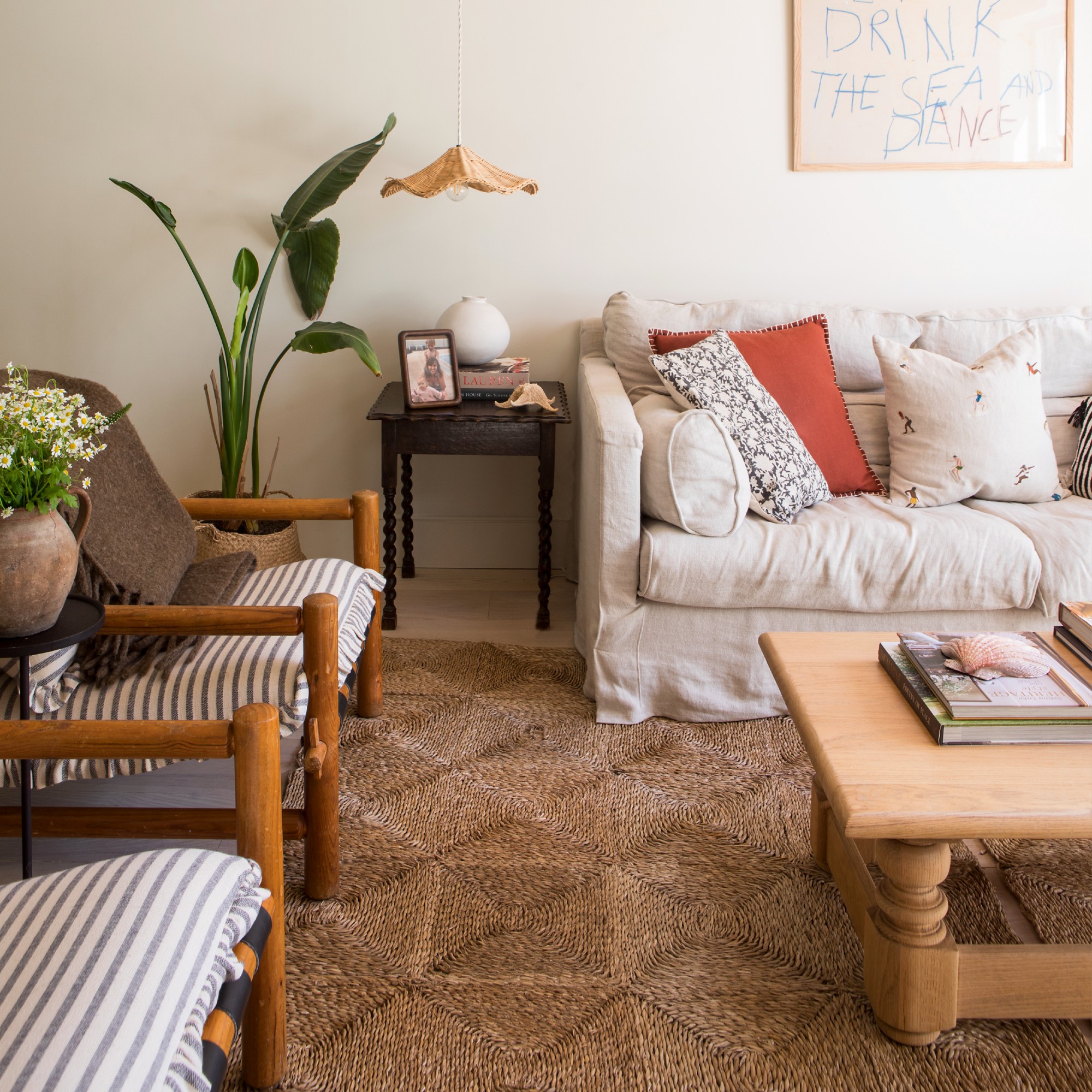 A living room with a cream sofa and a large jute rectangular rug underneath