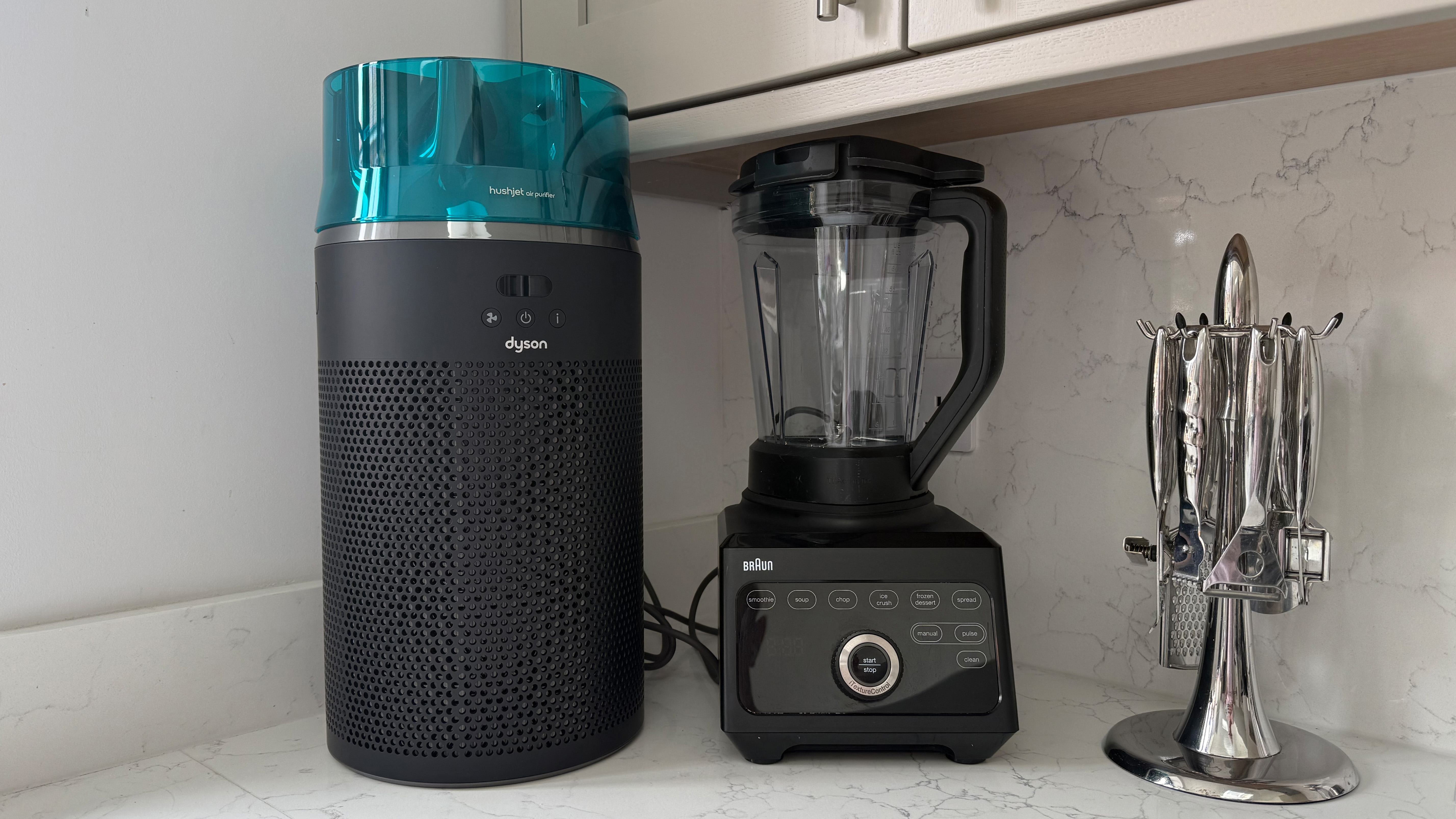 Dyson HushJet air purifier standing on a kitchen countertop next to a Braun blender and utensil holder for scale comparison
