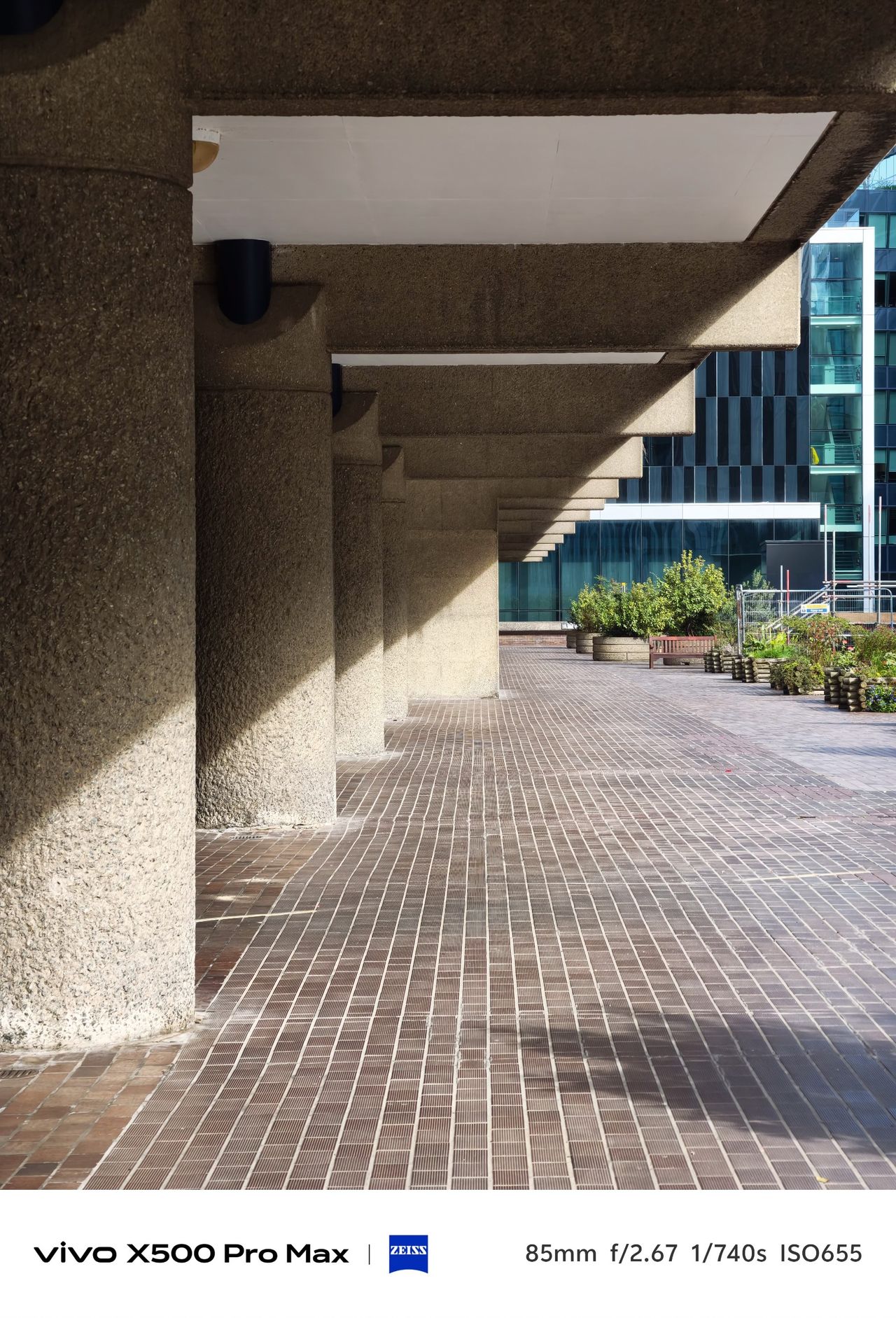 Repeating concrete columns and angular shadows beneath a covered walkway at the Barbican.