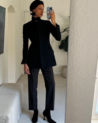 Fashion influencer Tylynn Nguyen wearing a black jacket, beret, trousers, and heeled boots.