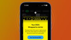 An iPhone on an orange and yellow background showing a Spotify Wrapped 2024 teaser message