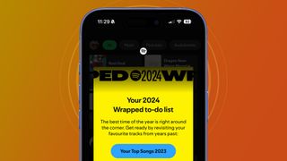 An iPhone on an orange and yellow background showing a Spotify Wrapped 2024 teaser message