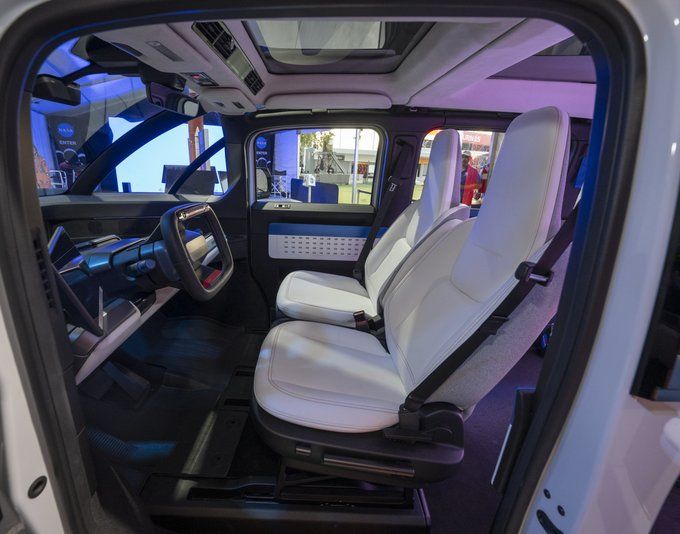 A futuristic interior of a vehicle is shown with black floors and white seats.