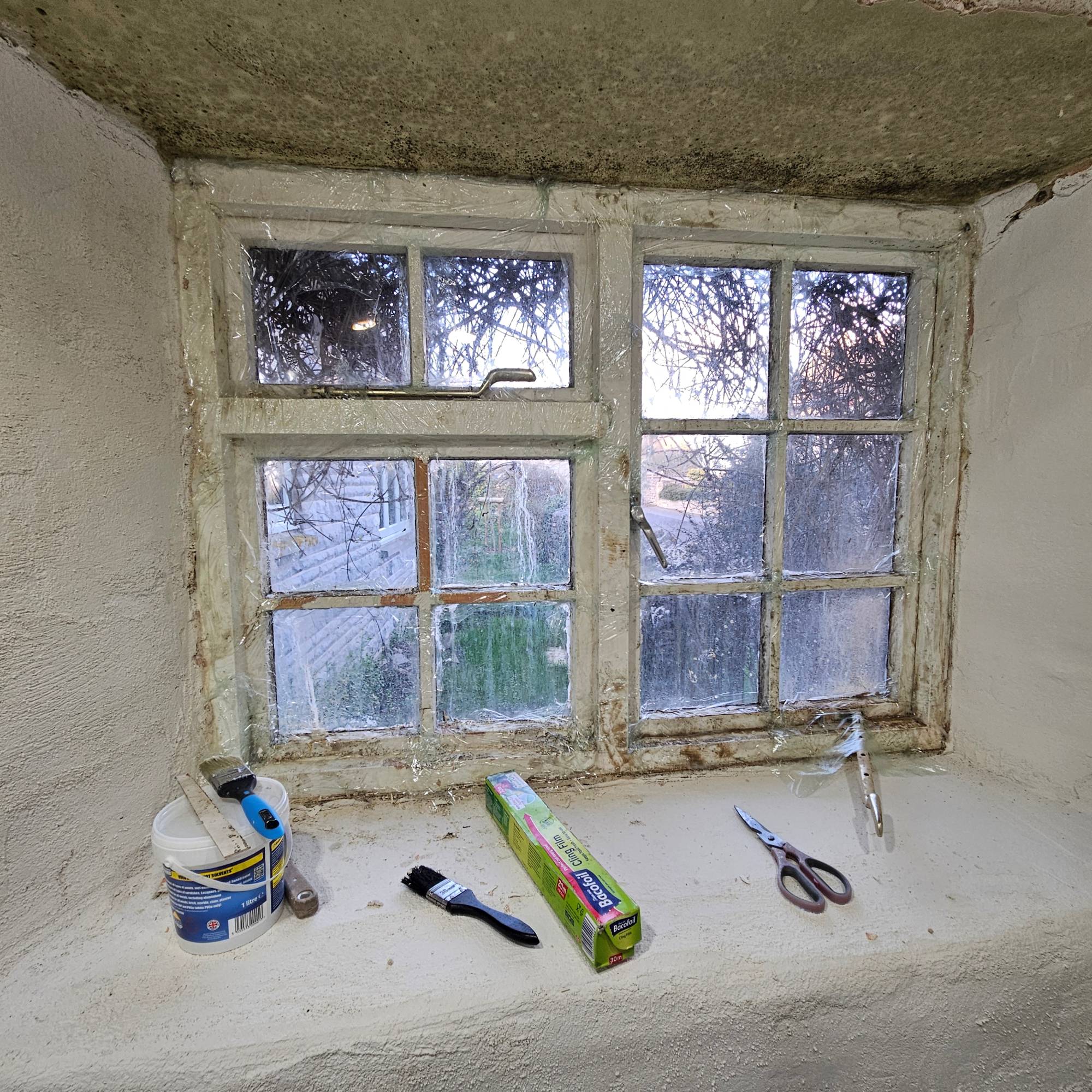 white window wrapped in clingfilm with paint stripper