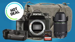 Pentax K-1 II camera kit with battery grip, 64GB SanDisk Extreme PRO SD card, and 28-105mm lens, on a blue background with a "Hot Deal" badge in front of a blue background