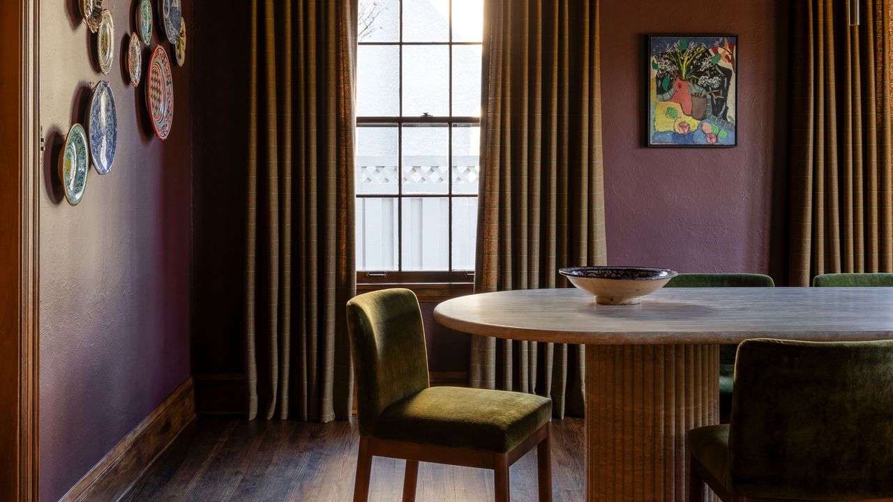 a dark red painted dining room with a yellow accent chairs and curtains