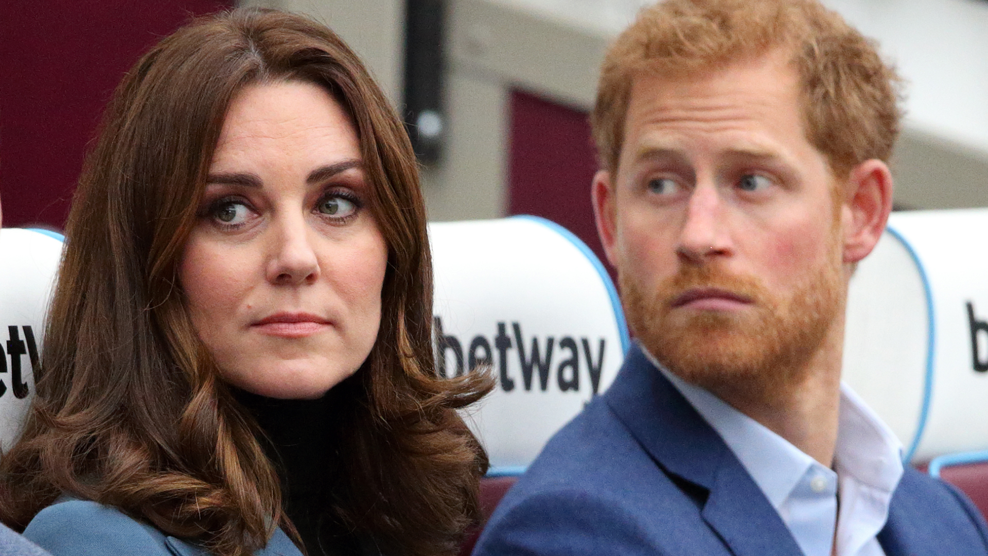 Kate Middleton wears a turquoise jacket and has bouncy dark brown hair and Prince Harry has red hair and beard