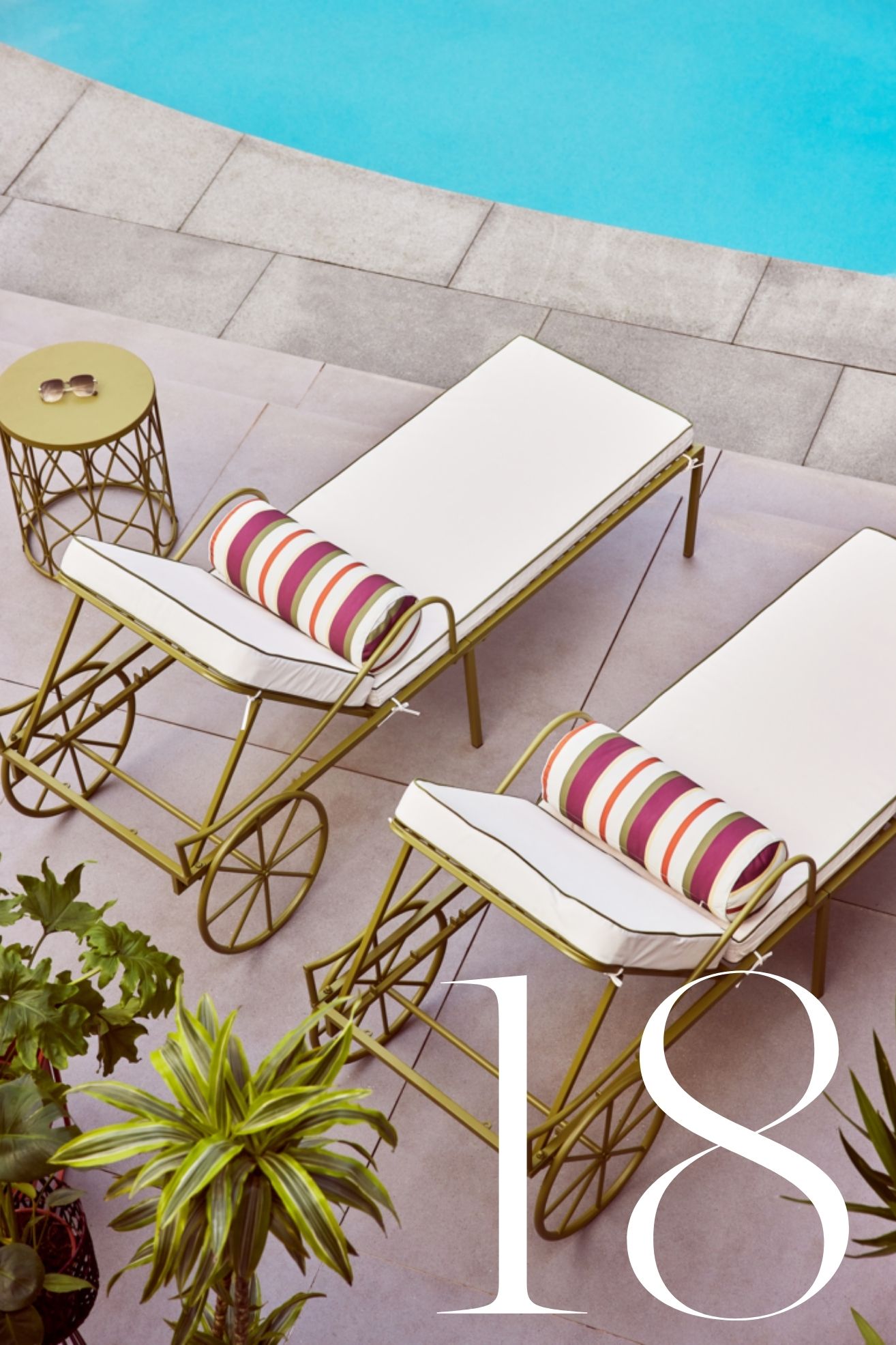 two garden loungers with green wheels and a side table next to a pool with potted plants