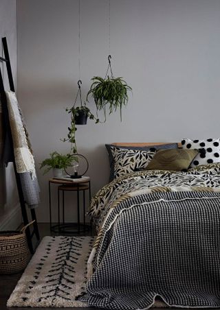 Bedroom with warm grey walls, black and white pattern bedding with green underside