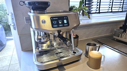 Sage Oracle Jet coffee machine with cup of coffee and milk pitcher on kitchen counter