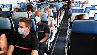 Volunteer medical workers and firemen sit in their plane with masks prior to flying to French overseas department of Martinique and Guadeloupe amid the Covid-19 pandemic, at the Orly airport in Orly, near Paris, on August 20, 2021.