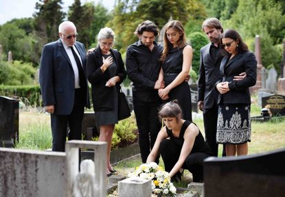 Family members standing graveside at a funeral