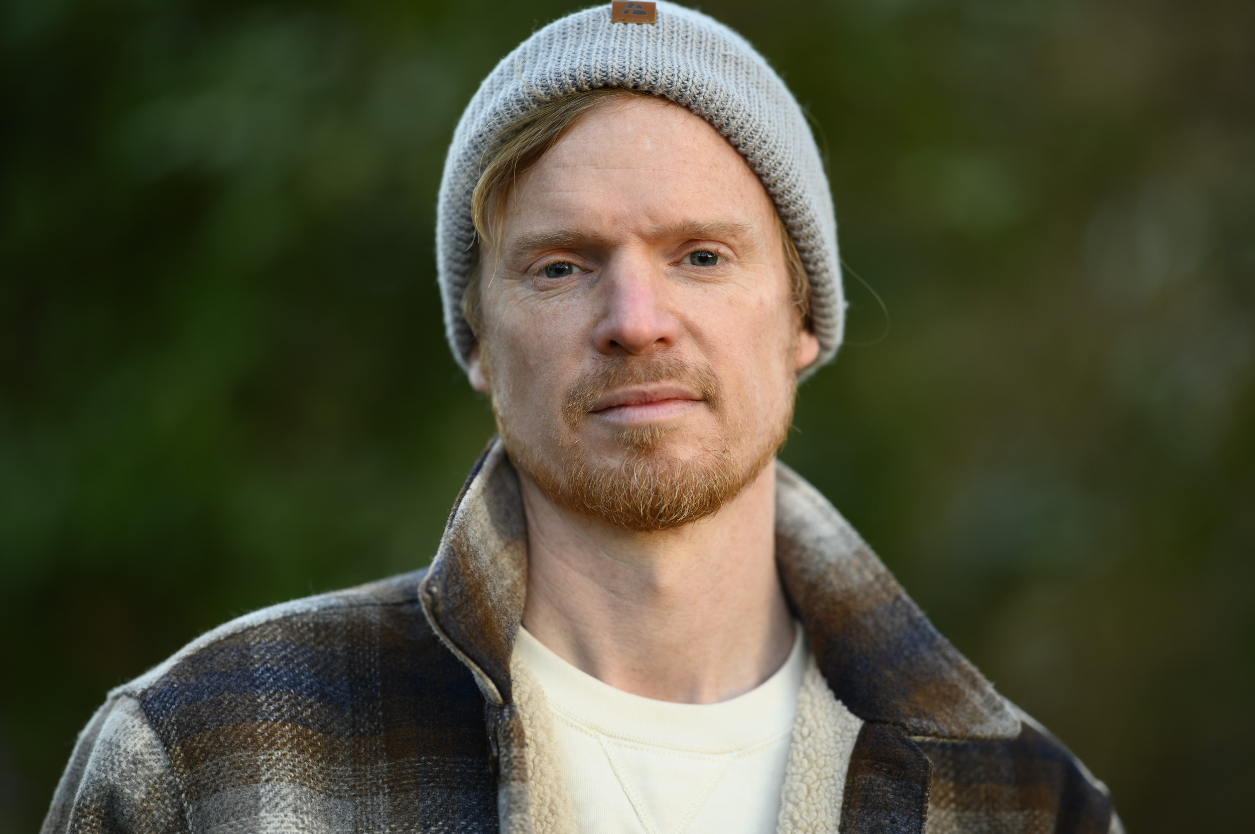 Portraits of a man in a beanie hat and shacket and golden hour with dappled light in background