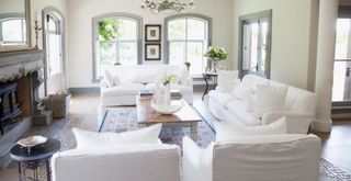 white living room with white linen covered couches arranged to face inwards with armchairs as a layout suggested for how to make a living room look expensive