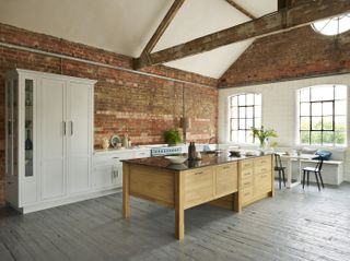 A large kitchen with a vaulted ceiling, exposed brick walls, and a wooden kitchen island