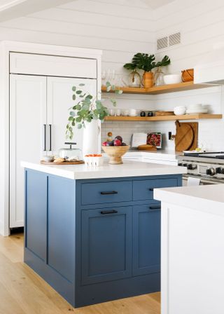 beach house kitchen with blue island and open shelves with white walls