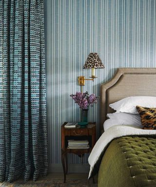 Blue bedroom with striped wallpaper and green bedspread