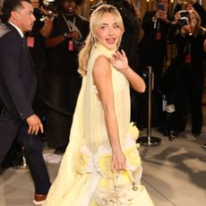 An image of Sabrina Carpenter wearing butter yellow to Dior's Cruise 2027 show. 