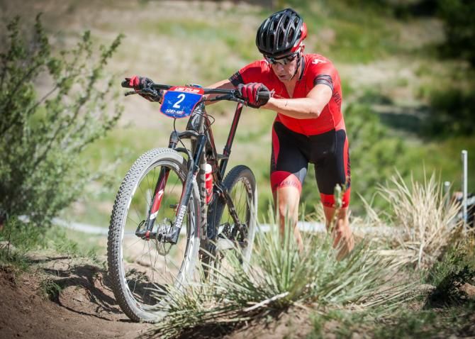 Todd Wells (Specialized) dismounts and runs his bike during the opening laps of the elite men's cross country race.
