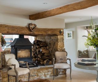 Wood burning stove in entrance hall with pair of Louis XV chairs and round console table