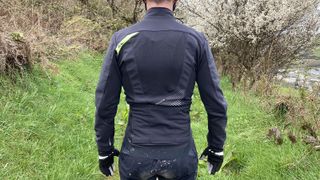 Rear of mountain biker wearing Rockrider Slim-Fit Softshell Mountain Biking Jacket