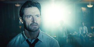 Hugh Jackman watches a projection intently in Remiinscence.