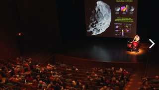 A presentation at a Northeast Astronomy Forum: The celestial body projected onto the screen is Phoebe, a natural satellite orbiting the planet Saturn.